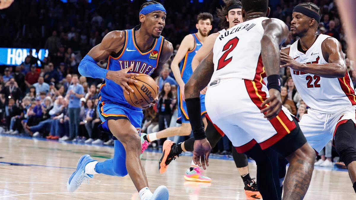 Shai Gilgeous-Alexander (izq.), guardia del Thunder, conduce a la canasta ante la marca de Jimmy Butler (22) y Terry Rozier, del Heat de Miami, durante la segunda mitad del partido celebrado en el Paycom Center en Oklahoma City, el 8 de marzo de 2024.
