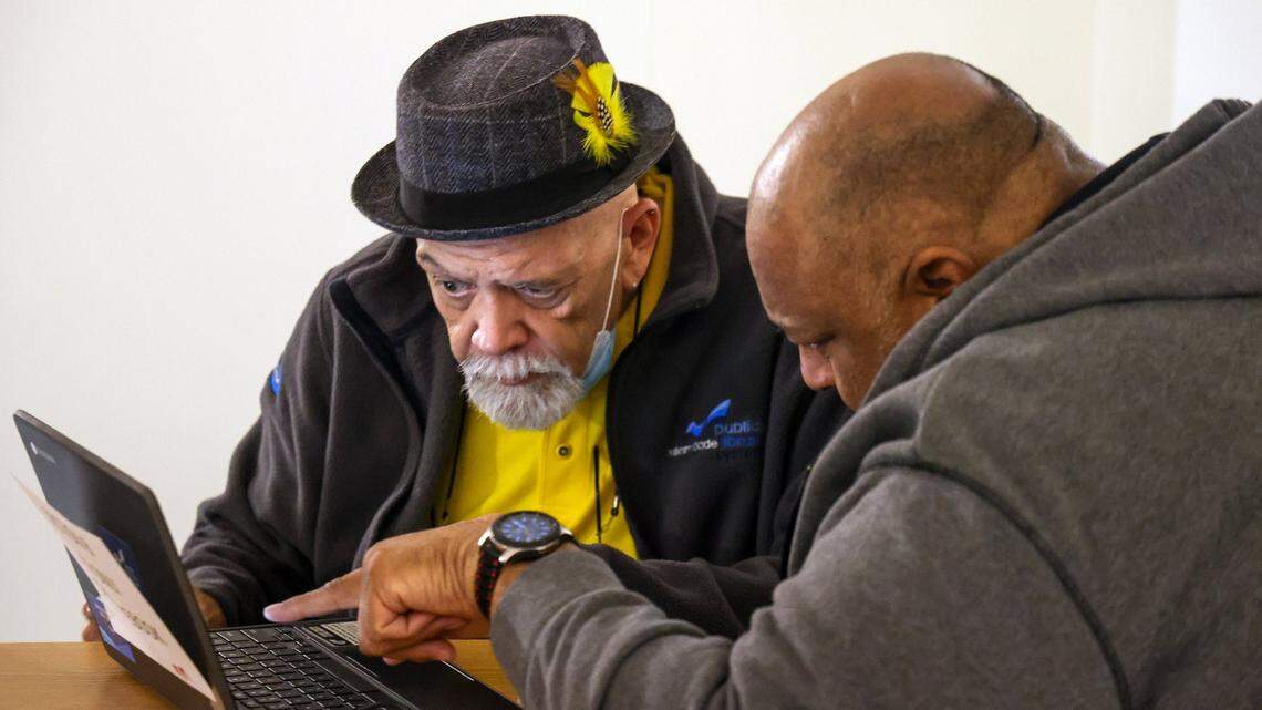 Reference librarian Richard Cortina helps Jesus Sanchez with the county’s Section 8 Housing Choice Voucher application that allows eligible residents to apply for housing assistance on Monday, Feb. 5, 2024, at the Miami-Dade Main Library in downtown Miami.
