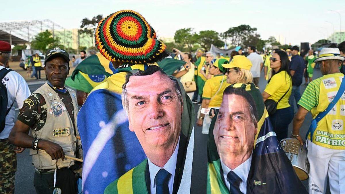 TOPSHOT - Supporters of former Brazilian President Jair Bolsonaro wrapped in flags bearing his image take part in a march calling for amnesty for those convicted of attempting a coup d'Ã©tat in Brasilia on October 7, 2025. (Photo by Evaristo Sa / AFP) (Photo by EVARISTO SA/AFP via Getty Images)          