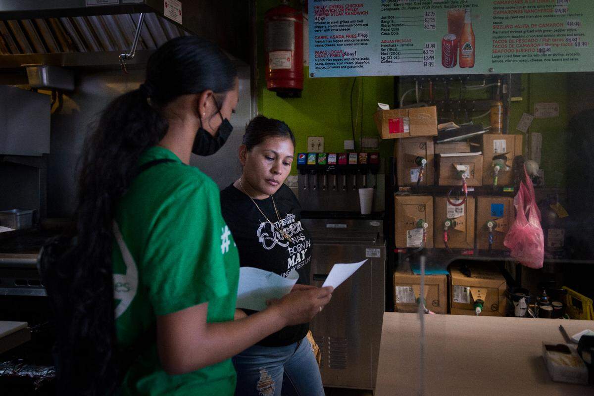 Melissa López explica el proceso de prueba de covid a un empleado de una taquería en Fresno, California, como parte de su capacitación como educadora de salud.