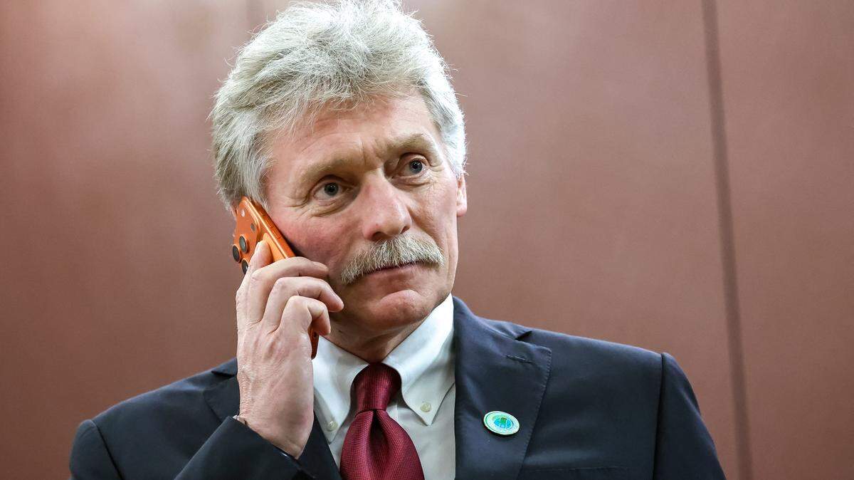 En esta fotografía de grupo distribuida por la agencia estatal rusa Sputnik, el portavoz del Kremlin, Dmitri Peskov, utiliza un teléfono inteligente mientras asiste a una reunión del presidente de Rusia con el presidente de Irán en Asjabad, el 12 de diciembre de 2025.