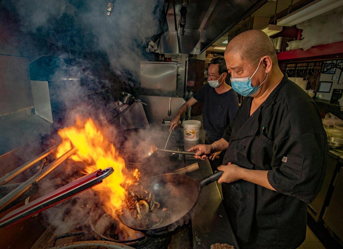 El chef Ming, al frente, y el chef Wai, cocinan en woks en el restaurant Qianlong, fundado en el 2007.
