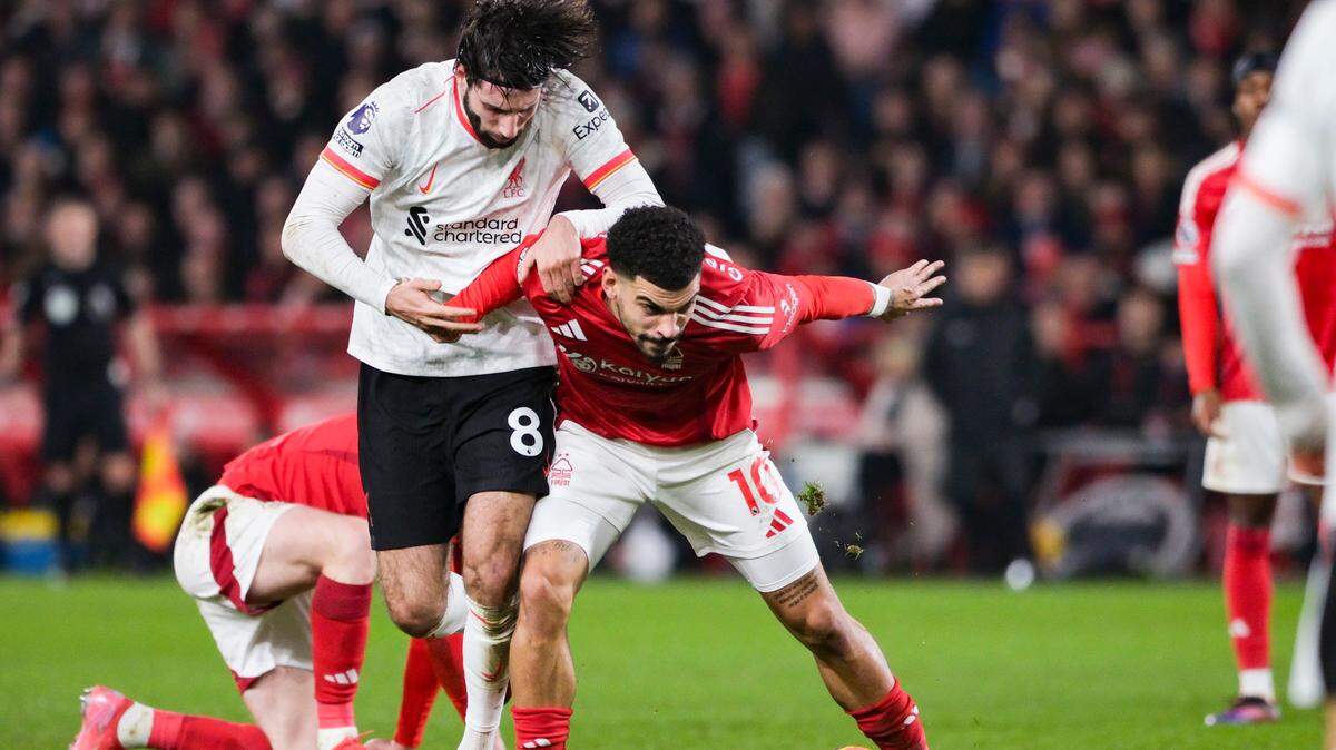 El jugador del Nottingham Forest Morgan Gibbs-White (der.) lucha por la pelota con Dominik Szoboszlai, de Liverpool, en el partido de la liga inglesa celebrado el 14 de enero de 2025 en Nottingham, Inglaterra.