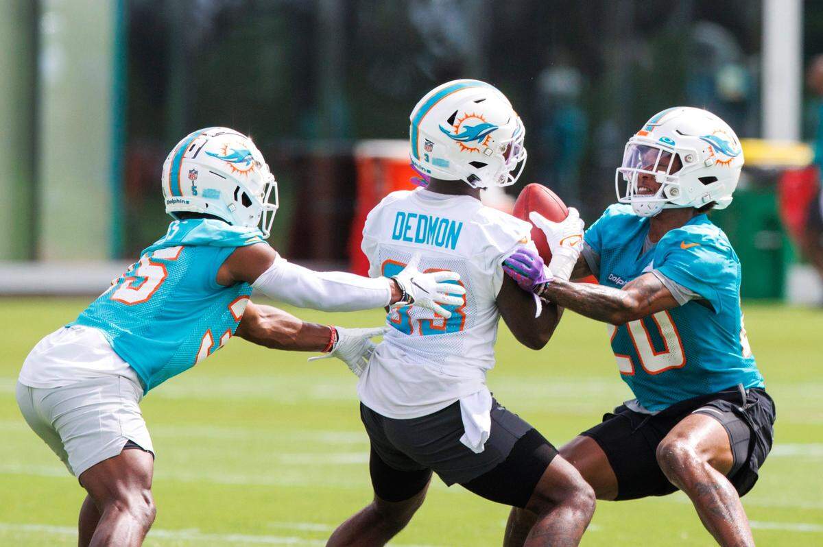 El wide receiver de los Dolphins DeVonte Dedmon (83) trata de salir de la marca del defensive back DAngelo Ross (izq.) y el safety Sheldrick Redwine, en la práctica del equipo celebrada el 27 de julio de 2022 en Miami Gardens, Florida.