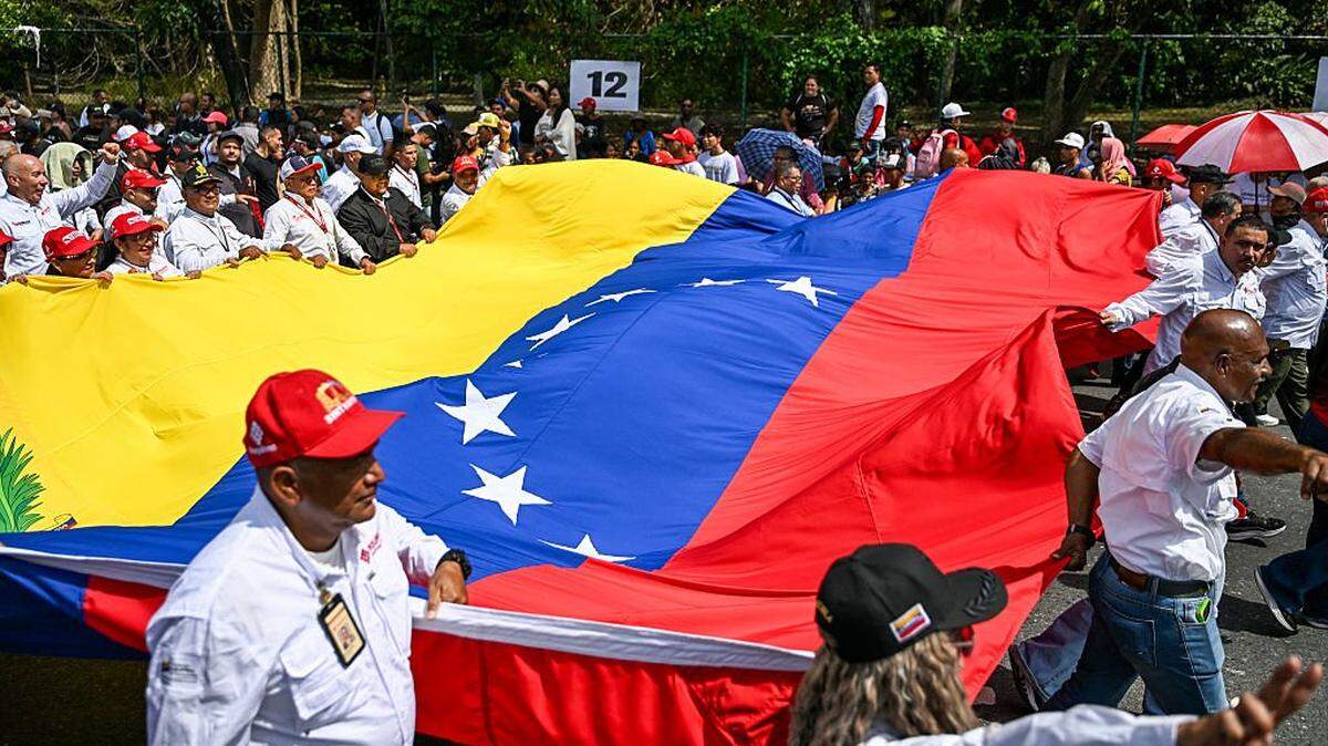 Manifestantes exhiben una bandera venezolana durante una marcha que exige el levantamiento de todas las sanciones estadounidenses, en Caracas, el 30 de abril de 2026. Delcy Rodríguez anunció el 30 de abril un aumento salarial del 26% en el denominado “ingreso mínimo integral”, elevándolo de 190 a 240 dólares mensuales; se trata del primer ajuste desde la caída de Nicolás Maduro.