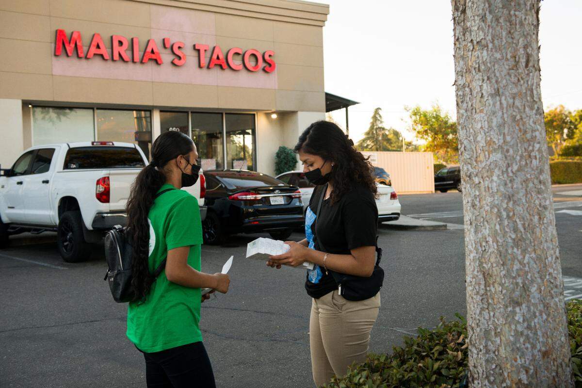 Melissa López (izq) y Alma Gallegos se preparan para distribuir pruebas de covid en una taquería en Fresno, California. Ambas son estudiantes del último año de Theodore Roosevelt High School y participan en el programa Promotoritos, una pasantía organizada por la organización sin fines de lucro Fresno Building Healthy Communities.
