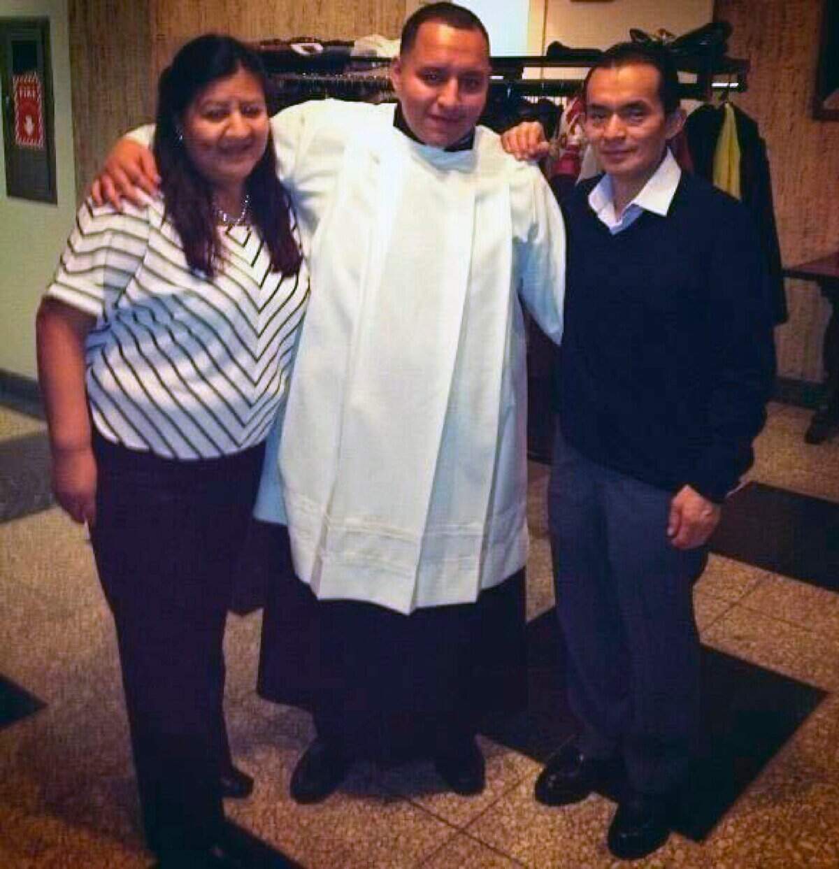 In this December 2014 handout provided by Rev. Joseph Dutan, Dutan poses with his mother, Ana, and father, Manuel at seminary in the Queens borough of New York. Rev. Joseph Dutan recently lost his father, Manuel Dutan, to coronavirus. (Courtesy of Joseph Dutan via AP)