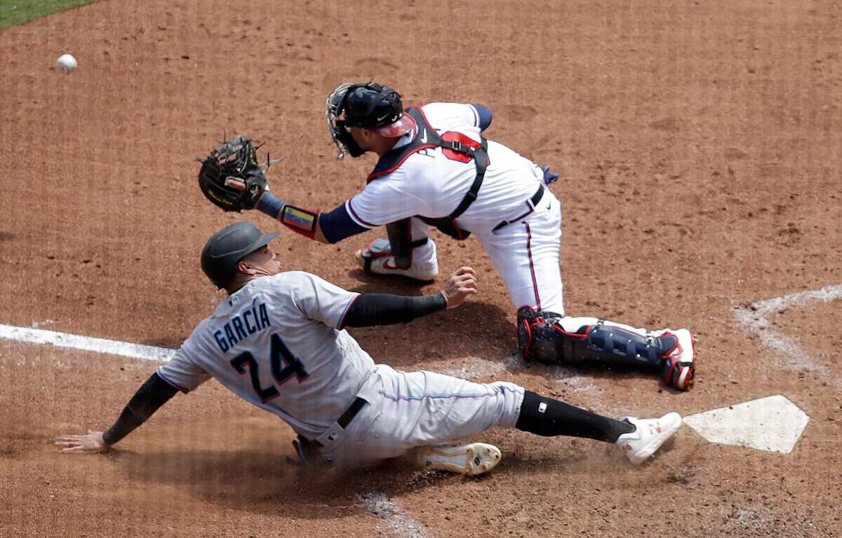 El jardinero de los Marlins Avisail García anota una carrera en una jugada con el receptor de los Bravos Manny Piña, en el quinto inning del partido celebrado el 24 de abril de 2022 en Atlanta.