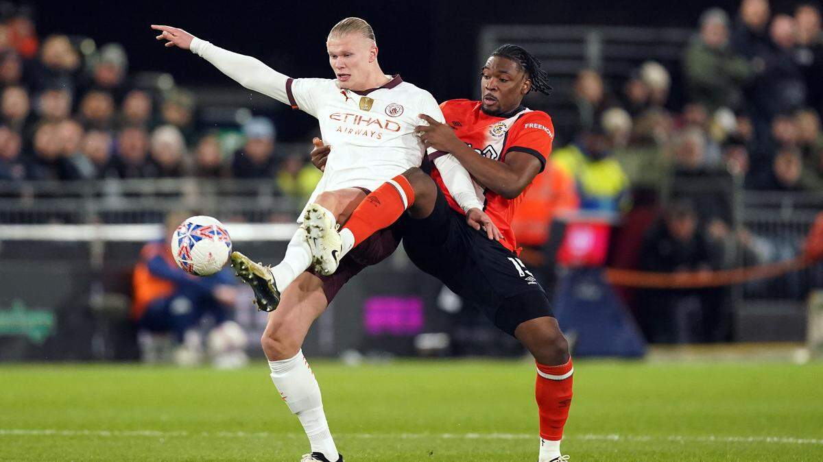El jugador del Manchester City Erling Haaland (izq.) y el jugador de Luton Town Teden Mengi, luchan por la pelota en el partido celebrado el 27 de febrero de 2024 en Manchester.