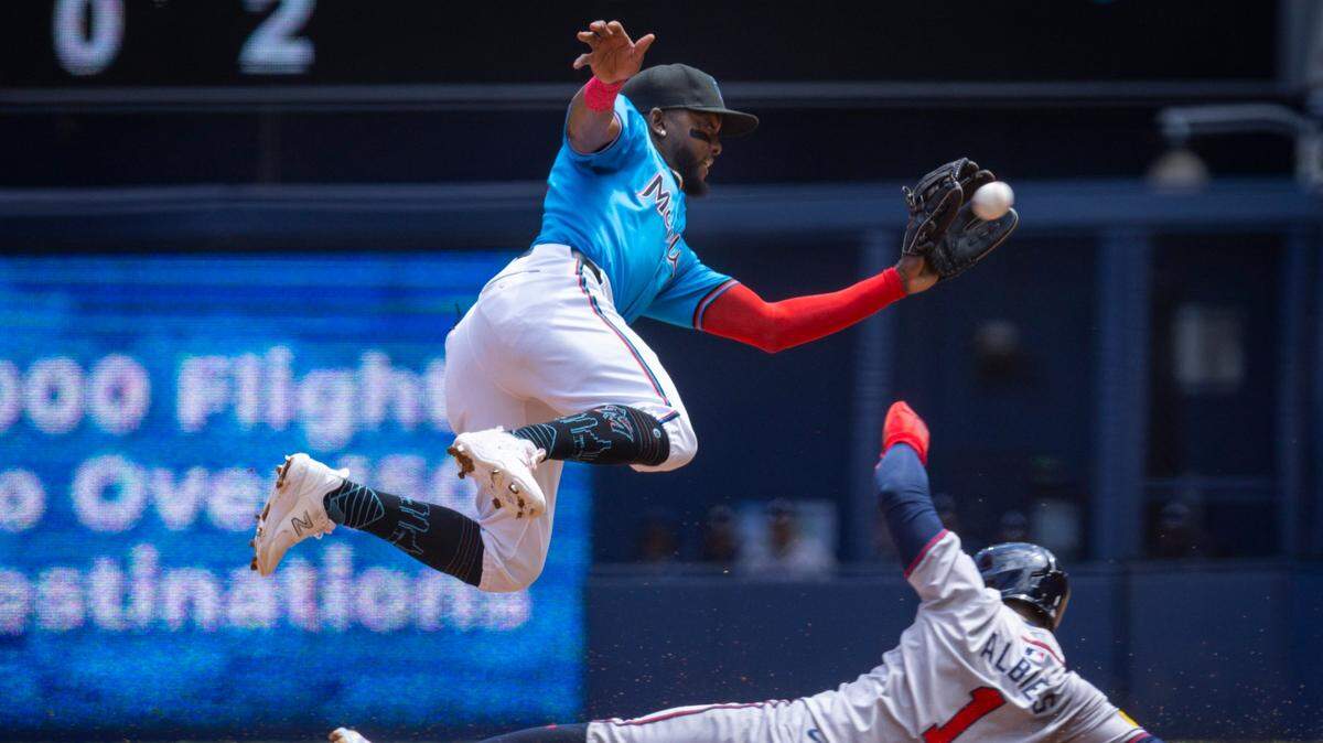 El torpedero de los Marlins Vidal Bruján captura la pelota, pero no puede impedir que Ozzie Albies, de los Bravos de Atlanta, se robe la segunda base en el tercer inning del partido celebrado el 14 de abril de 2024 en Miami.