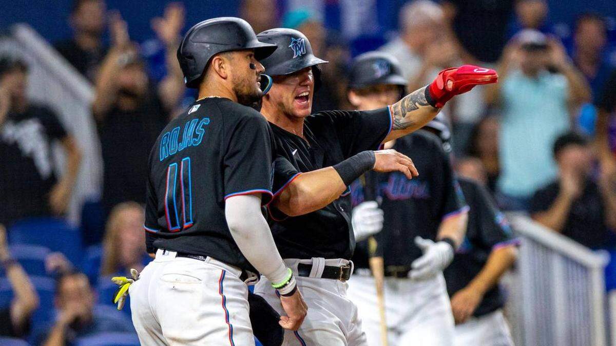Los jugadores de los Marlins Peyton Burdick (86) y Miguel Rojas (11) reaccionan al anotar una carrera tras un doblete de Joey Wendle (18) durante la sexta entrada de un partido contra los Dodgers de Los Ángeles el viernes 26 de agosto de 2022. 
