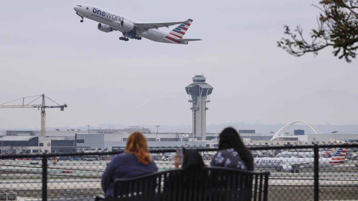 LOS ANGELES, CALIFORNIA - NOVEMBER 12: People watch from an overlook as an American Airlines plane takes off near the air traffic control tower at Los Angeles International Airport (LAX) on November 12, 2025 in Los Angeles, California. The Federal Aviation Administration (FAA) has reduced flights by 10 percent in 40 major airports around the country, including LAX, with airlines warning that flight disruptions could continue even after the end of the federal government shutdown as the Thanksgiving holiday approaches. (Photo by Mario Tama/Getty Images)