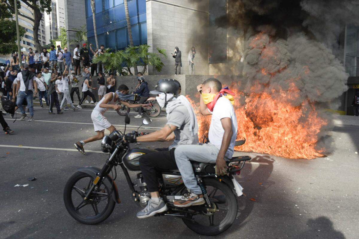 Un motociclista pasa cerca de cauchos incendiados por manifestantes que protestan en contra de la cuestionada reelección del gobernante venezolano Nicolás Maduro, el lunes 29 de julio de 2024, en Caracas. 