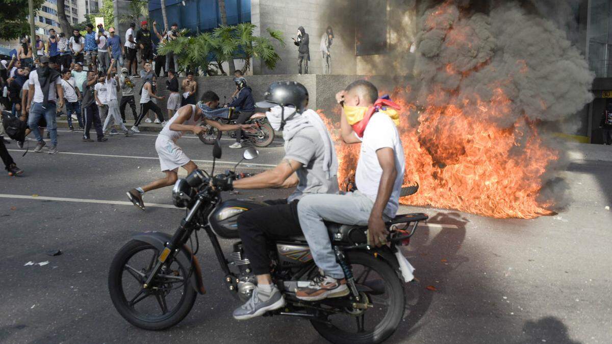 Un motociclista pasa cerca de cauchos incendiados por manifestantes que protestan en contra de la cuestionada reelección del gobernante venezolano Nicolás Maduro, el lunes 29 de julio de 2024, en Caracas.