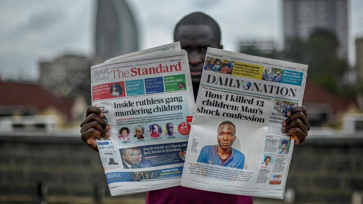Un hombre sostiene dos periódicos diarios (The Standard, Daily Nation) que llevan titulares sobre un asesino involucrado en la muerte de al menos 10 niños en Nairobi, Kenia, el 15 de julio de 2021