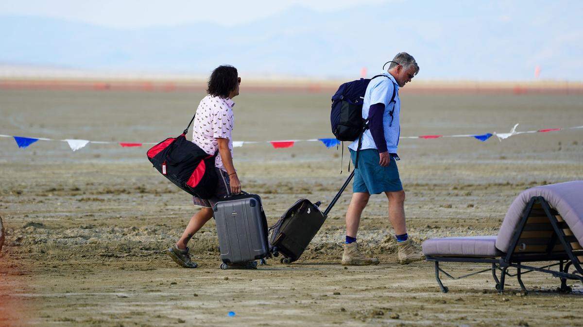 Dos personas con su equipaje se dirigen hacia los límites del lugar donde se celebra el festival Burning Man, en Nevada, el domingo 3 de septiembre de 2023.