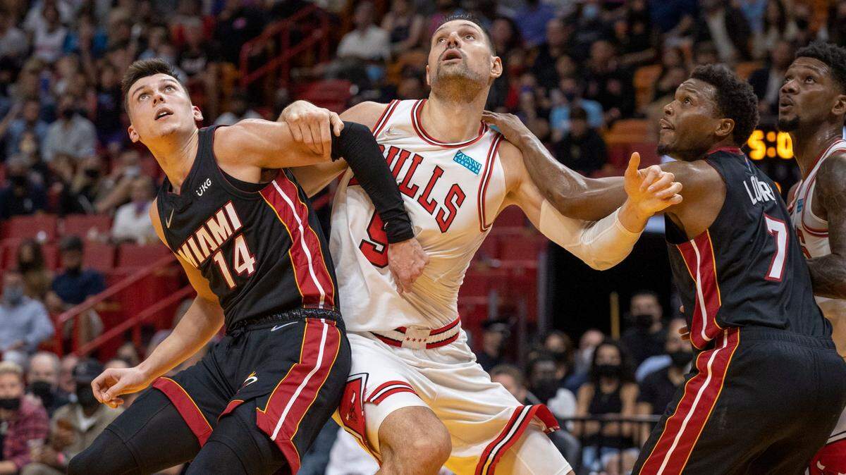 Los defensas del Heat Tyler Herro (14) y Kyle Lowry (7) luchan con el centro de los Bulls Nikola Vucevic (9) este sábado 1 de diciembre de 2021. en el FTX Arena de Miami.