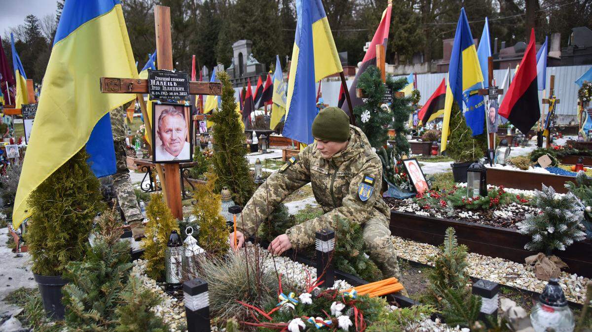 Un cadete militar coloca una vela en la tumba de un soldado ucraniano que murió en la invasión de Rusia, el 2 de febrero de 2024, en Leópolis, Ucrania.