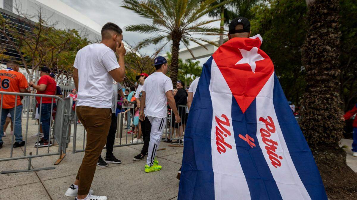 EN MIAMI, un hombre que lleva una bandera cubana con el lema de Patria y Vida camina hacia la entrada del LoanDepot Park antes del partido de béisbol entre Cuba y los Estados Unidos.
