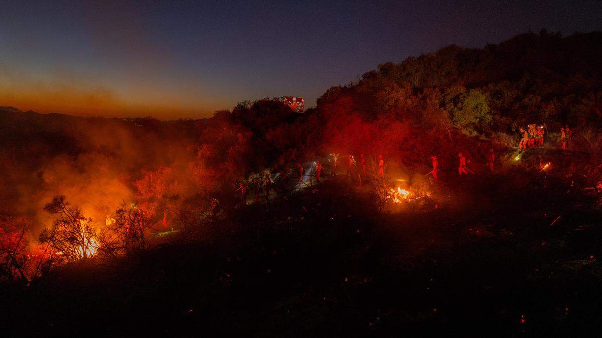 Los bomberos trabajan mientras el humo se eleva debido al creciente incendio de Palisades en Los Ángeles, California, el 11 de enero de 2025.
