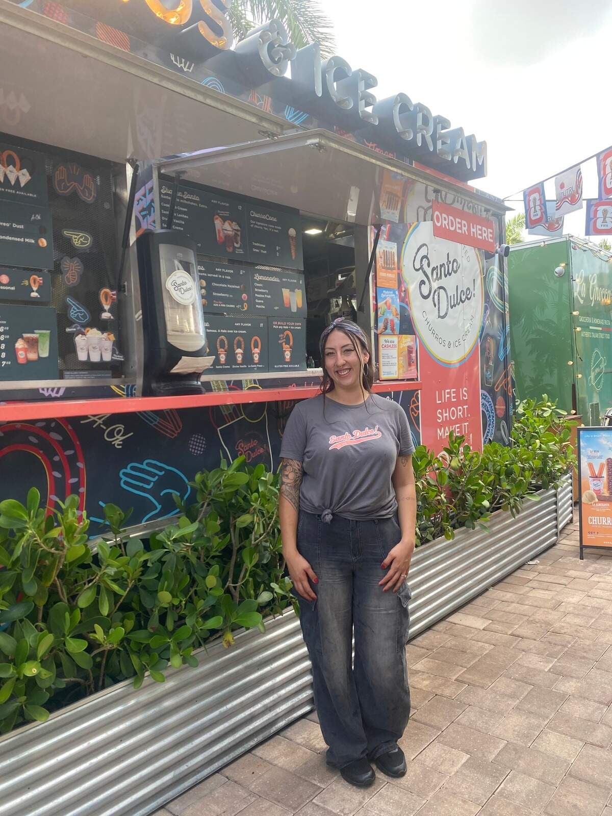Gabriela Mejía, gerente de Santo Dulce! en el puesto del negocio en The Doral Yard, donde se pueden probar los churros mundiales, hechos especialmente para celebrar equipos del Mundial de Fútbol, que se puede ver en las pantallas del patio.
