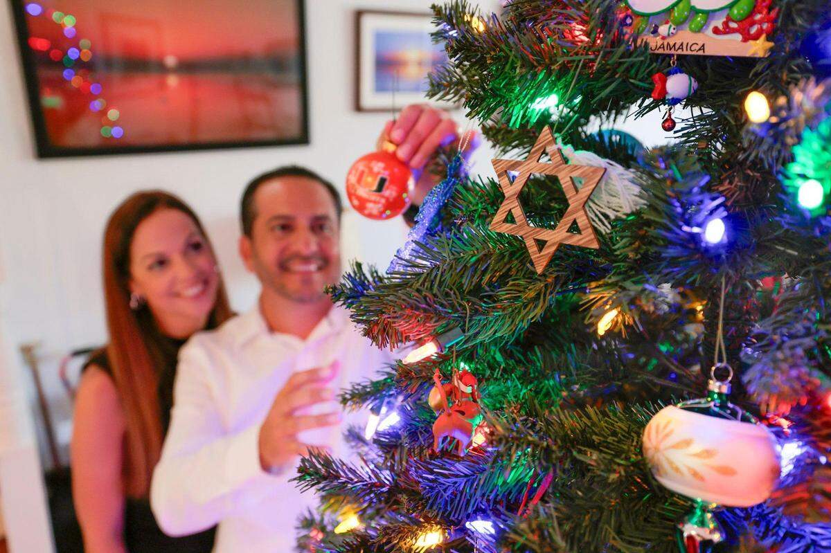 Sarah Robleto y Frank Robleto Jr. tienen diferentes orígenes religiosos (Sarah es judía y Frank es católico), por lo que celebran tanto la Navidad como Hanukkah mientras colocan adornos navideños en el árbol de Navidad en su casa en Cutler Bay, Florida, el sábado 21 de diciembre de 2024.