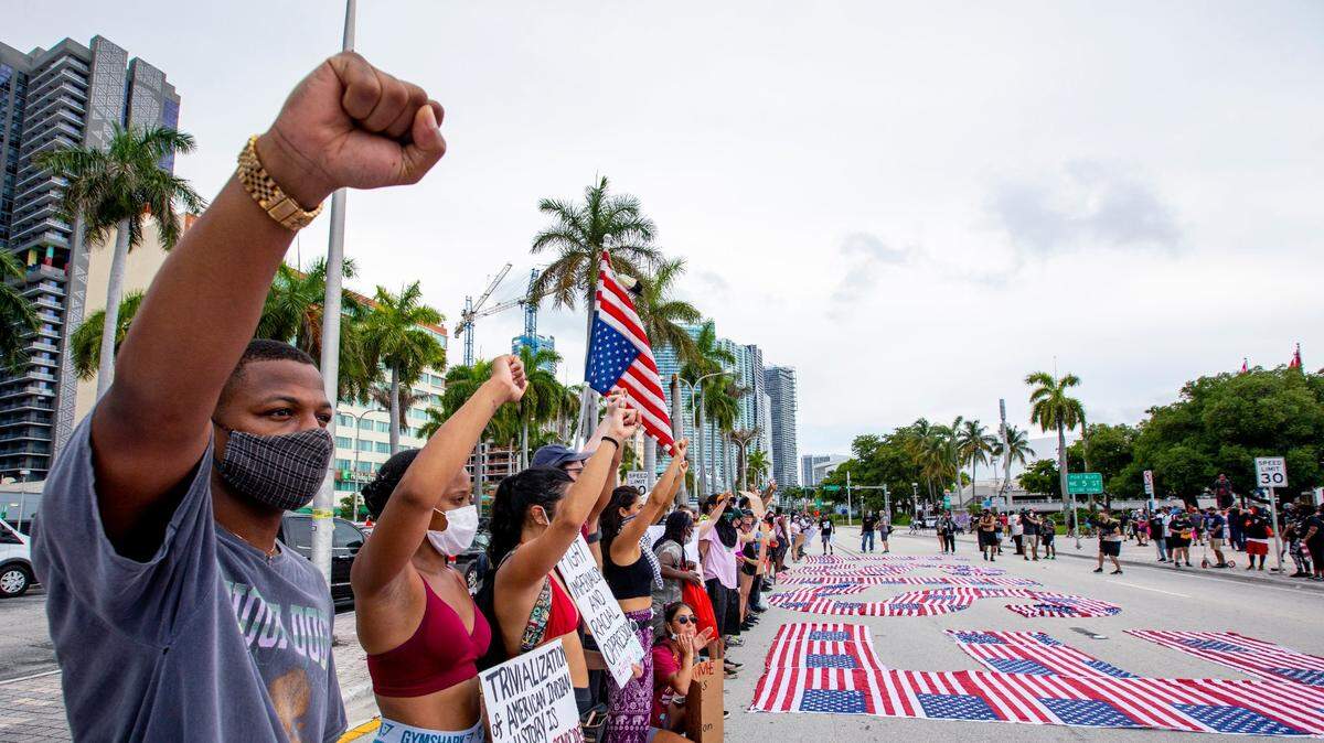 Manifestantes levanta un puño en el aire en apoyo al movimiento “Black Lives Matter”, el domingo 14 de junio de 2020 en Biscayne Boulevard, downtown Miami. Los manifestantes honraron el Día de la Bandera deletreando la palabra “RESIST” (Resistir) con banderas de Estados Unidos.