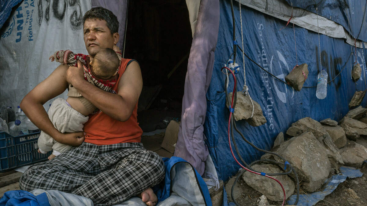 Rulam Heidari de Mazar-i-Sharif, Afghanistan, sujeta en brazos a su bebé de ocho meses frente a una tienda de campaña en Moria, Lesbos, Grecia. Traumas, psicosis e intentos de suicidio ocurren a menudo en este campamento de refugiados.