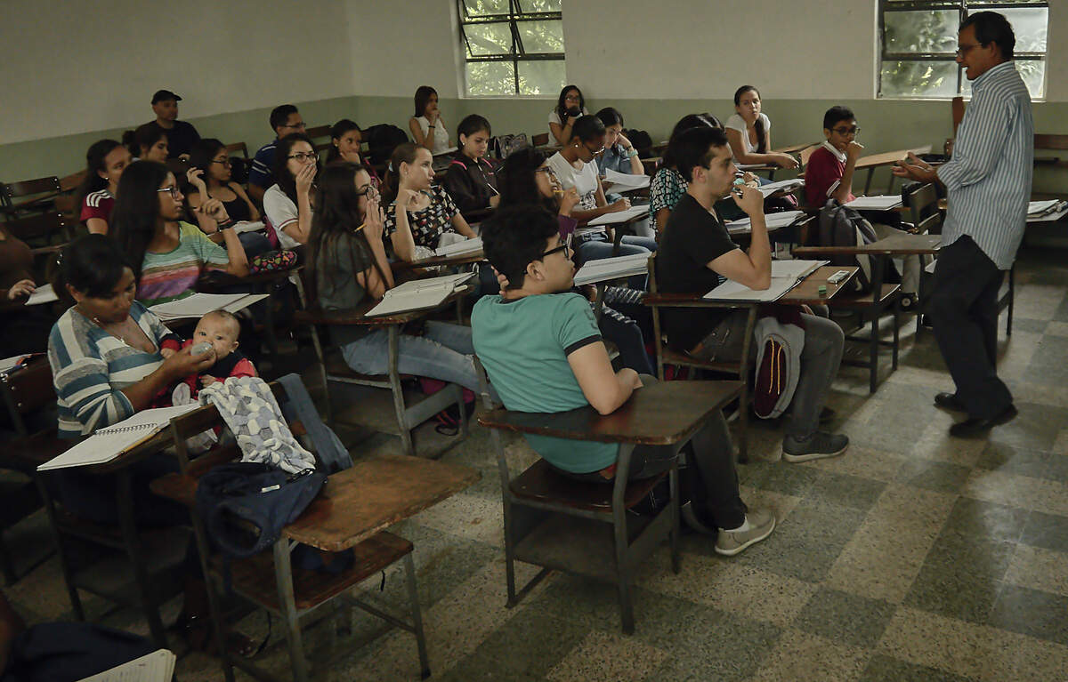 La estudiante Moraxis Granado alimenta a su bebé mientras asiste a una clase del profesor Carlos Molina en la Universidad Central de Venezuela en Caracas.