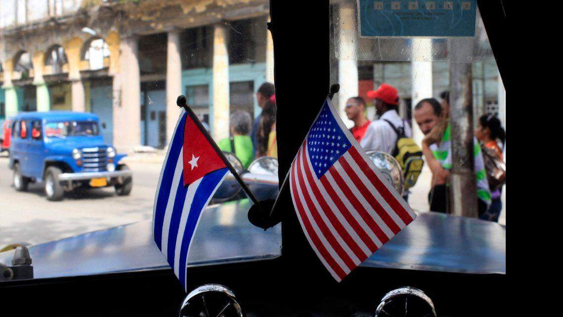 Fotografía de archivo del 22 de marzo de 2013 de dos pequeñas banderas de Cuba y Estados Unidos sobre el tablero de instrumentos de un automóvil en La Habana, Cuba.  AP