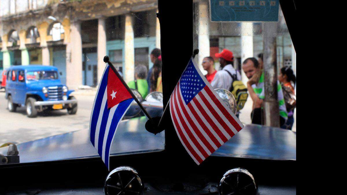 Fotografía de archivo del 22 de marzo de 2013 de dos pequeñas banderas de Cuba y Estados Unidos sobre el tablero de instrumentos de un automóvil en La Habana, Cuba.  AP