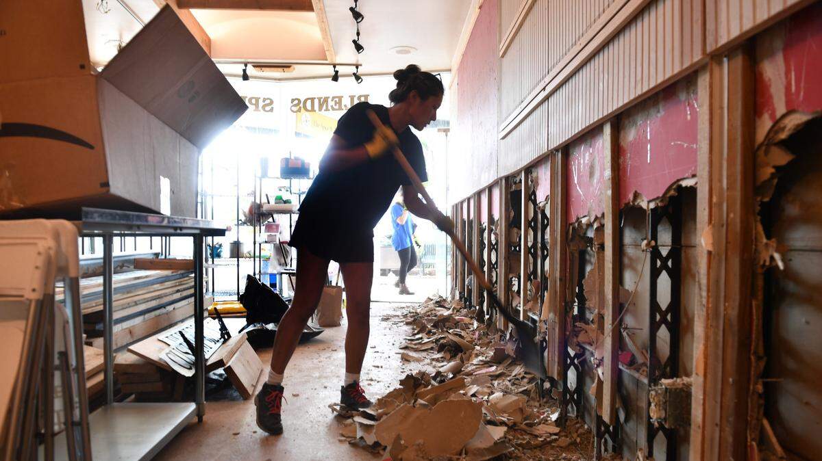 Jen Cover, la administradora de la tienda The Spice & Tea Exchange, en Sarasota, Florida, limpia los destrozos causados por los vientos del huracán Helene, el martes 1 de octubre de 2024.