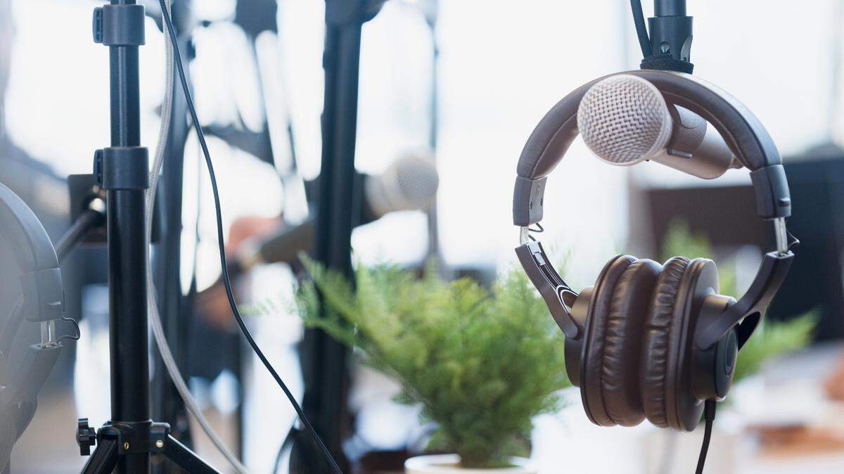 Una foto de cerca de unos auriculares colgados de un micrófono en un luminoso y alegre estudio de grabación.