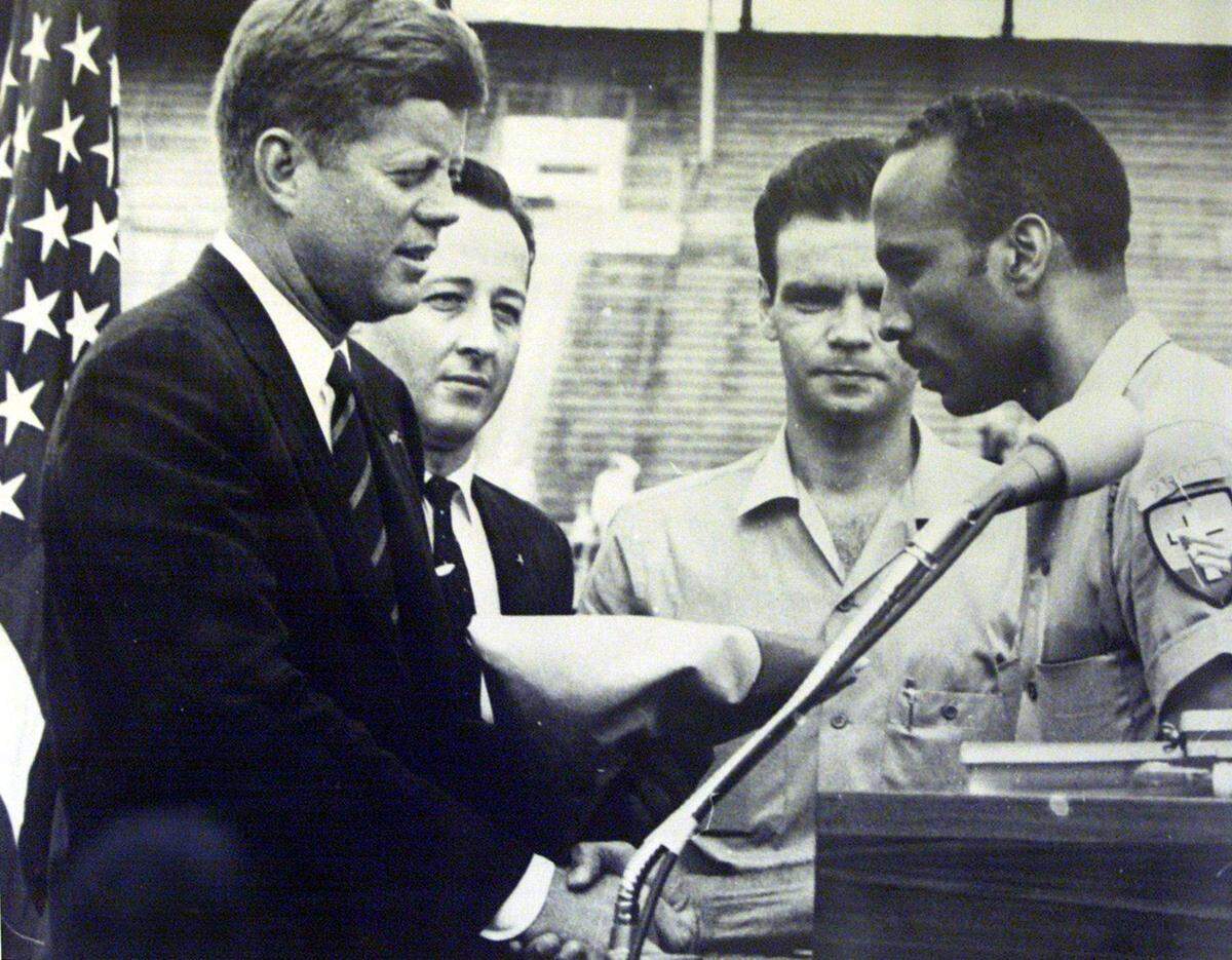 En esta foto de archivo, el general Erneido Oliva, quien fue el segundo al mando durante Bahía de Cochinos, entrega al presidente John F. Kennedy la bandera de la Brigada durante una visita a Miami en el Orange Bowl. Manuel Artime mira de atras. MIAMI HERALD