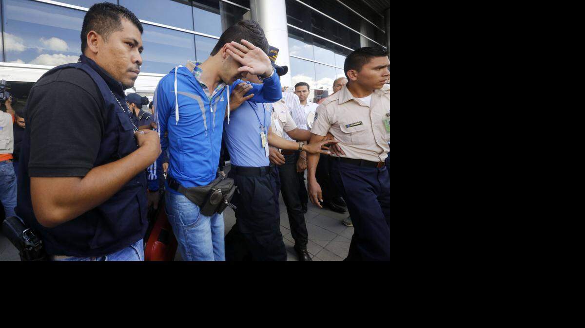 Policías trasladan a uno de los cinco ciudadanos sirios que fueron arrestados el miércoles en el Aeropuerto Internacional Tocontín en Tegucigalpa, Honduras. Los cinco hombres intentaban llegar a EEUU con pasaportes griegos robados. 