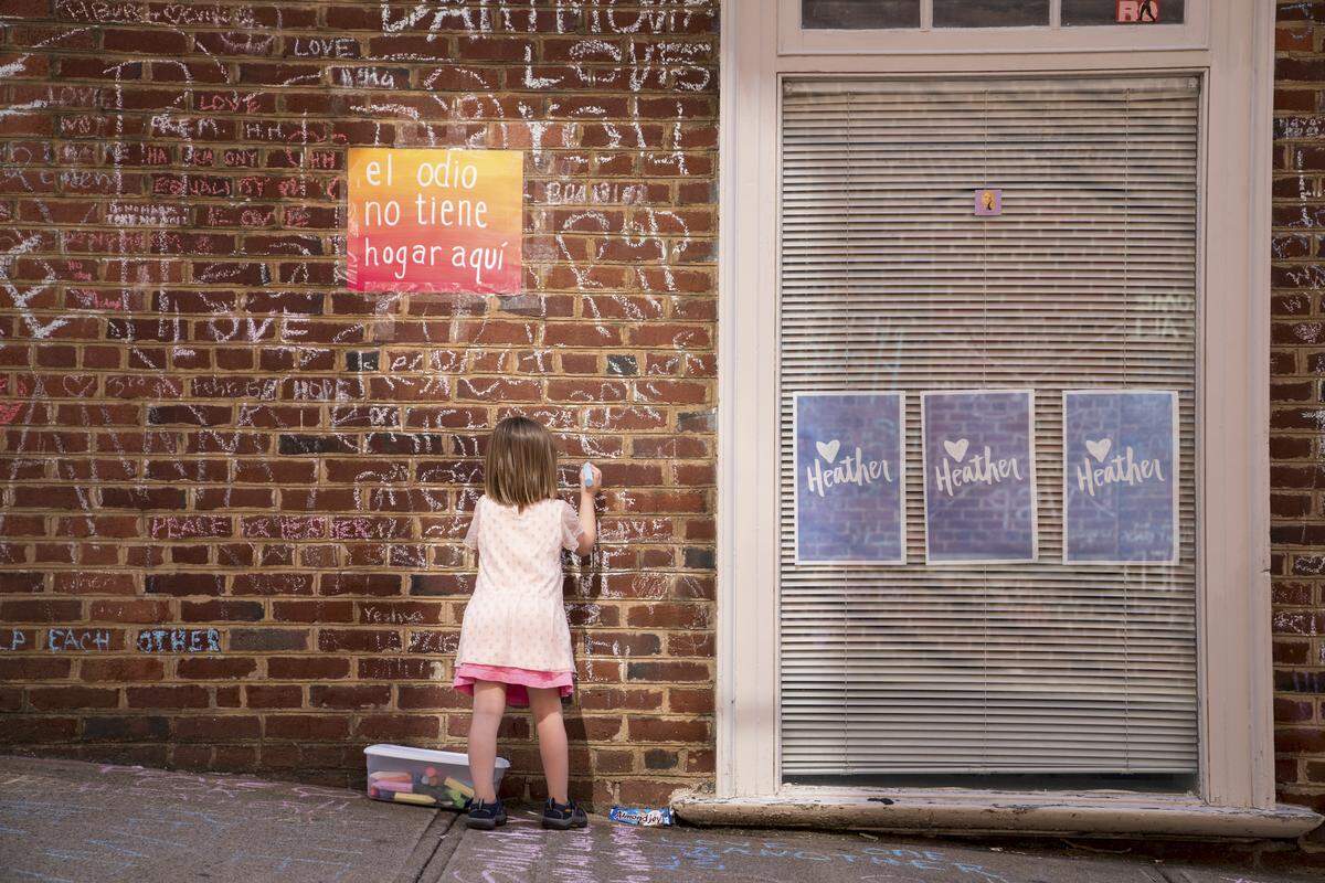Nora, de 2 años, escribe en la pared donde murió Heather Heyer el año pasado asesinada por un conductor que pertenecía al grupo de  “Unite the Right”, en Charlottesville, Virginia.