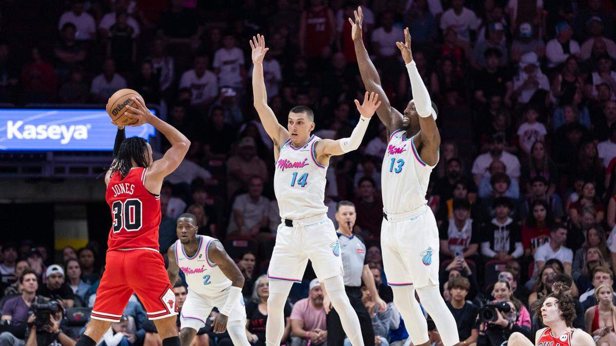 El jugador de los Bulls de Chicago Tre Jones trata de pasar la pelota ante la marca de Tyler Herro (14) y Bam Adebayo, en el partido de la NBA celebrado el 8 de marzo de 2025 en Miami.