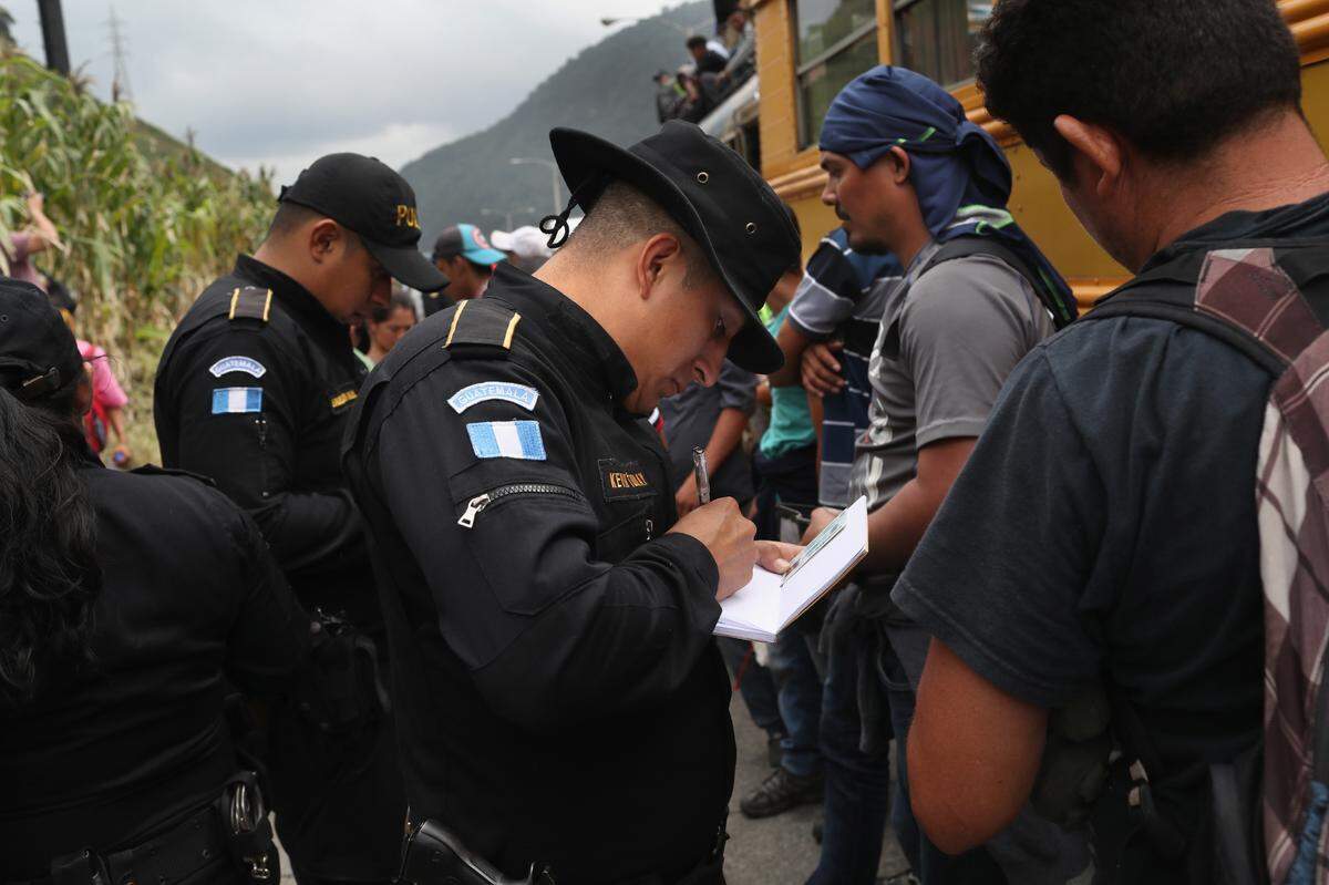 La Policía verifica la identidad de un grupo de migrantes en un punto de control en la ruta hacia la frontera con México, el 18 de octubre del 2018, en Palín, Guatemala.