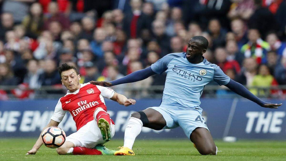 El jugador del Manchester City Yaya Touré (der.) lucha por la pelota con Mesut Ozil, del Arsenal, en un partido de la Copa FA el 23 de abril del 2017.