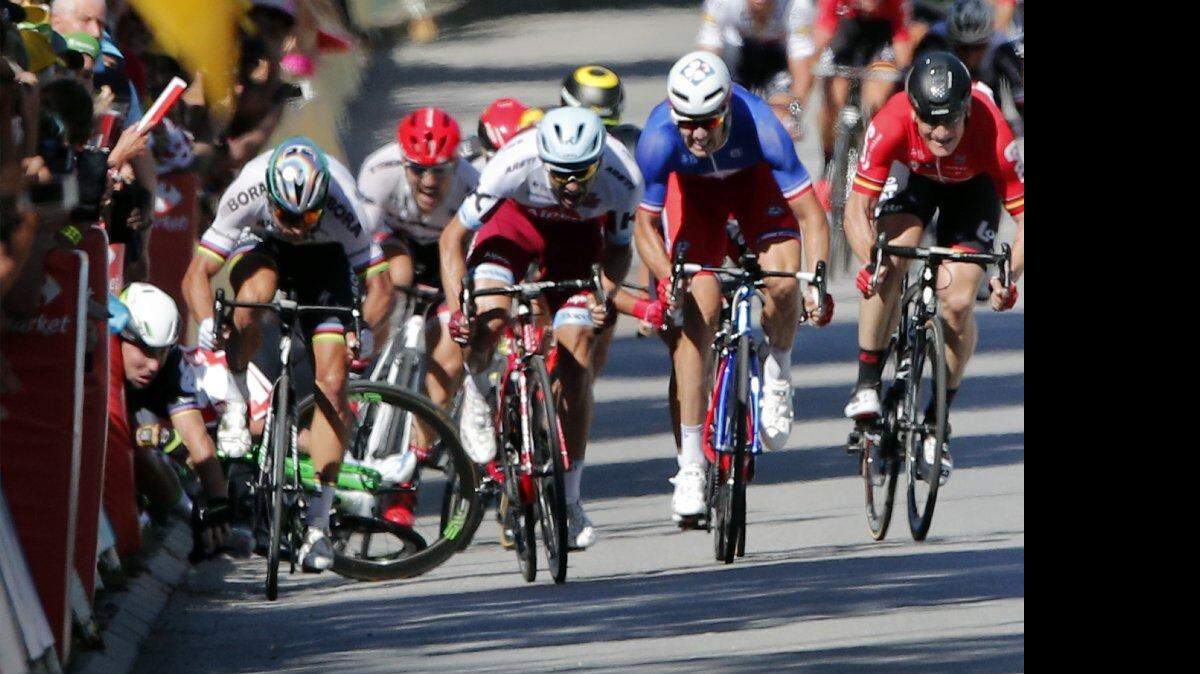 Mark Cavendish (izquierda) se golpea la cabeza contra la valla, al caer durante el sprint final de la cuarta etapa del Tour de Francia, el martes 4 de julio de 2017, en Vittel 