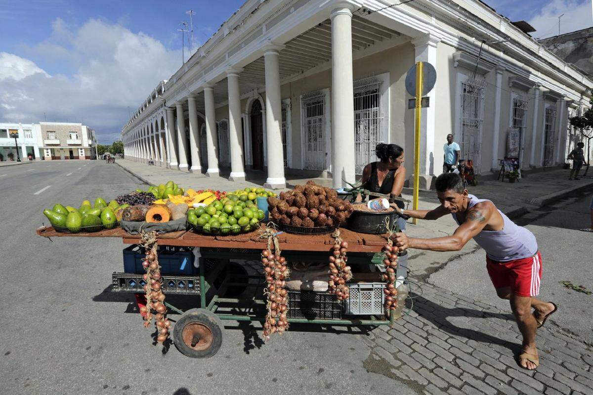 Santiago Fernández y Kenia González Torres empujan su carrito cargado de frutas y verduras para la venta en las calles de Cienfuegos.