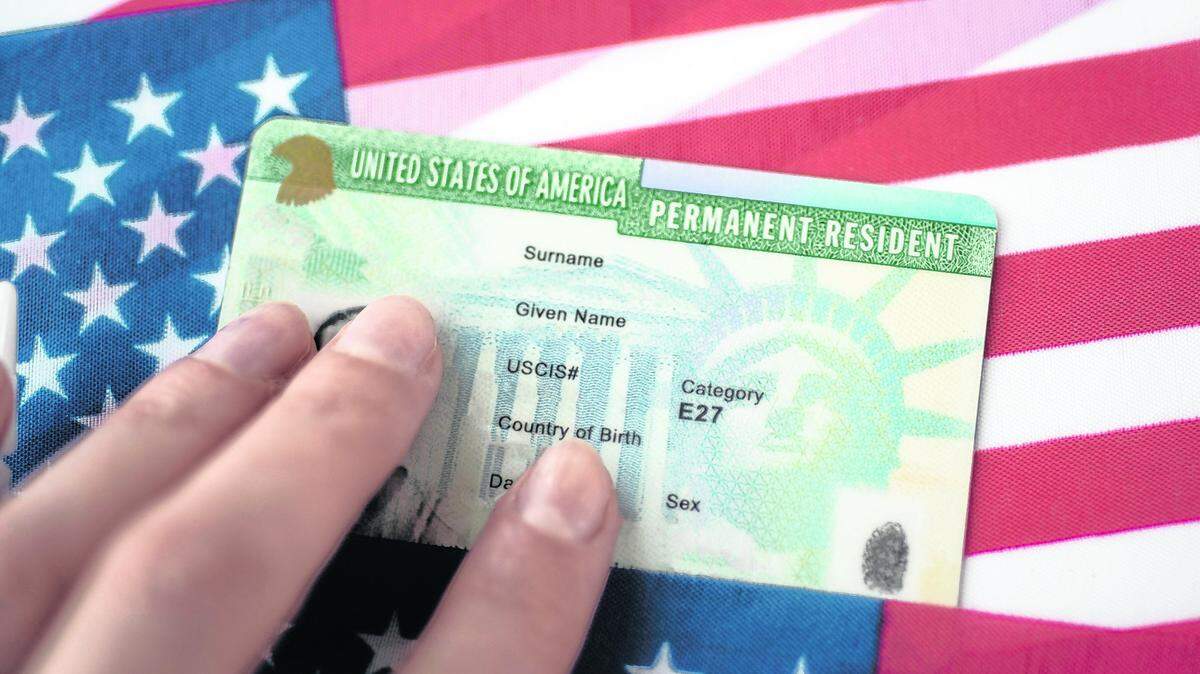 Permanent Resident Green card  of United states of America on flag of USA. Above close up view.