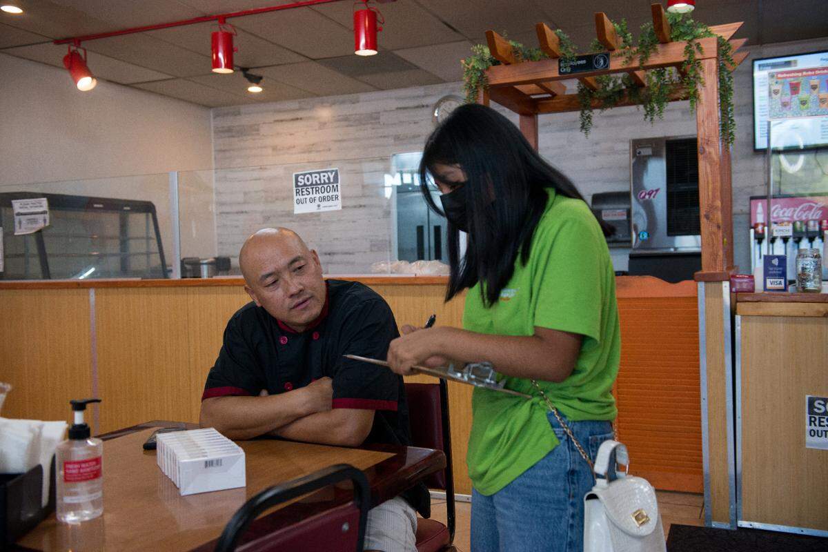 Jóvenes entregan pruebas de covid y folletos informativos a Chris Vang, propietario de Tiger Bite Bowls, un restaurante de fusión asiática en Fresno, California. Los jóvenes han sido capacitados como educadores de salud para promover las vacunas covid.