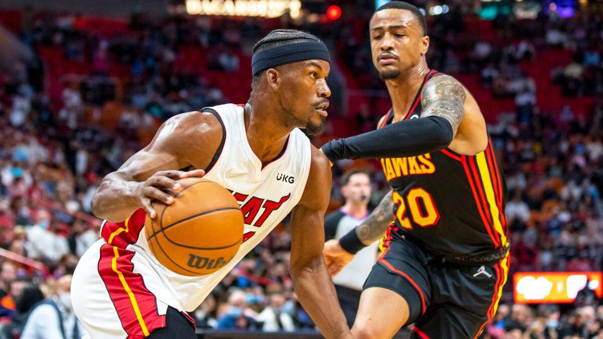 El delantero del Heat, Jimmy Butler (22), se escapa del jugador de los Hawks, John Collins (20), en el FTX Arena en el centro de Miami, Florida, el viernes 14 de enero de 2022.
