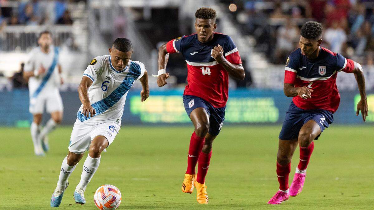 El jugador de Guatemala Carlos Mejía (izq.) trata de pasar la marca de los cubanos Neisser Sandó (centro) y Modesto Méndez, en el partido de la Copa Oro celebrado el 27 de junio de 2023 en el DRV PNK Stadium de Fort Lauderdale, Florida.