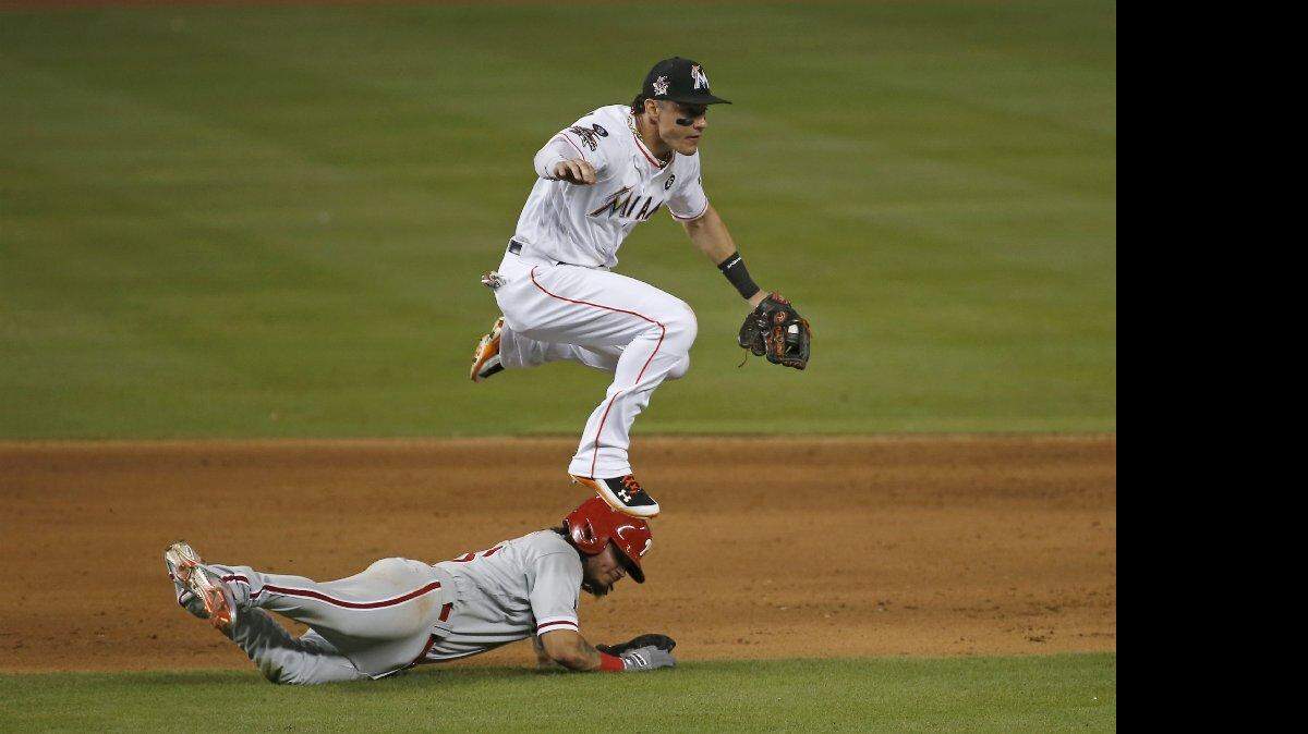 El tercera base de los Marlins Derek Dietrich salta sobre el torpedero de los Filis Freddy Galvis en una jugada del partido celebrado el 31 de agosto del 2017 en Miami.