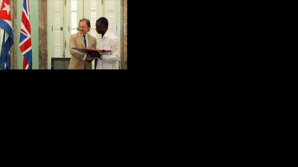 El secretario de Estado Británico de Exteriores, Hugo Swire (i), firma un acuerdo de cooperación con el vicepresidente primero del Instituto Nacional de Deportes, Educación Física y Recreación (INDER), Roberto León Richards (d), el jueves 30 de octubre de 2014, en La Habana (Cuba). EFE