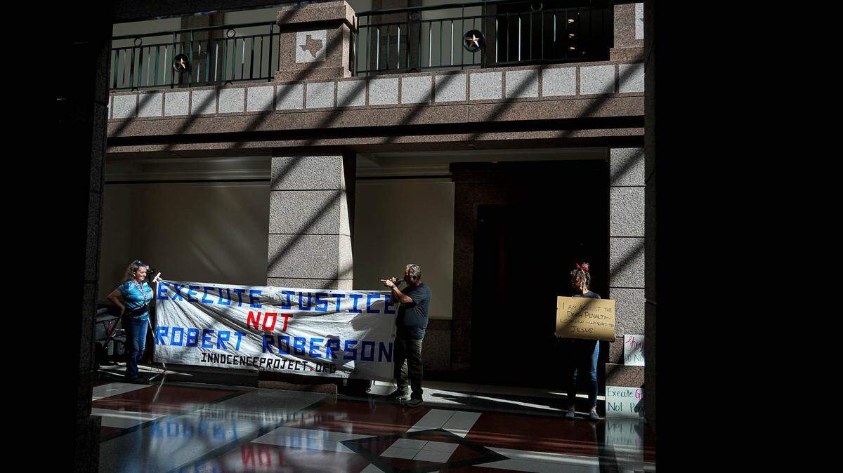 De izquierda a derecha, Amy Hedtke, Bob Smilie y Sam McRae protestan contra la ejecución de Robert Roberson durante una audiencia con el Comité de Jurisprudencia Judicial y Civil de la Cámara de Representantes de Texas en la Extensión del Capitolio de Texas el lunes 24 de octubre de 2024.