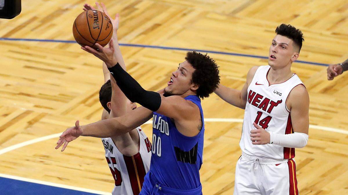 El delantero del Magic Aaron Gordon entra al aro entre los jugadores del Heat Tyler Herro (14) y Duncan Robinson (55), el 23 de diciembre de 2020 en el Amway Center, en Orlando.
