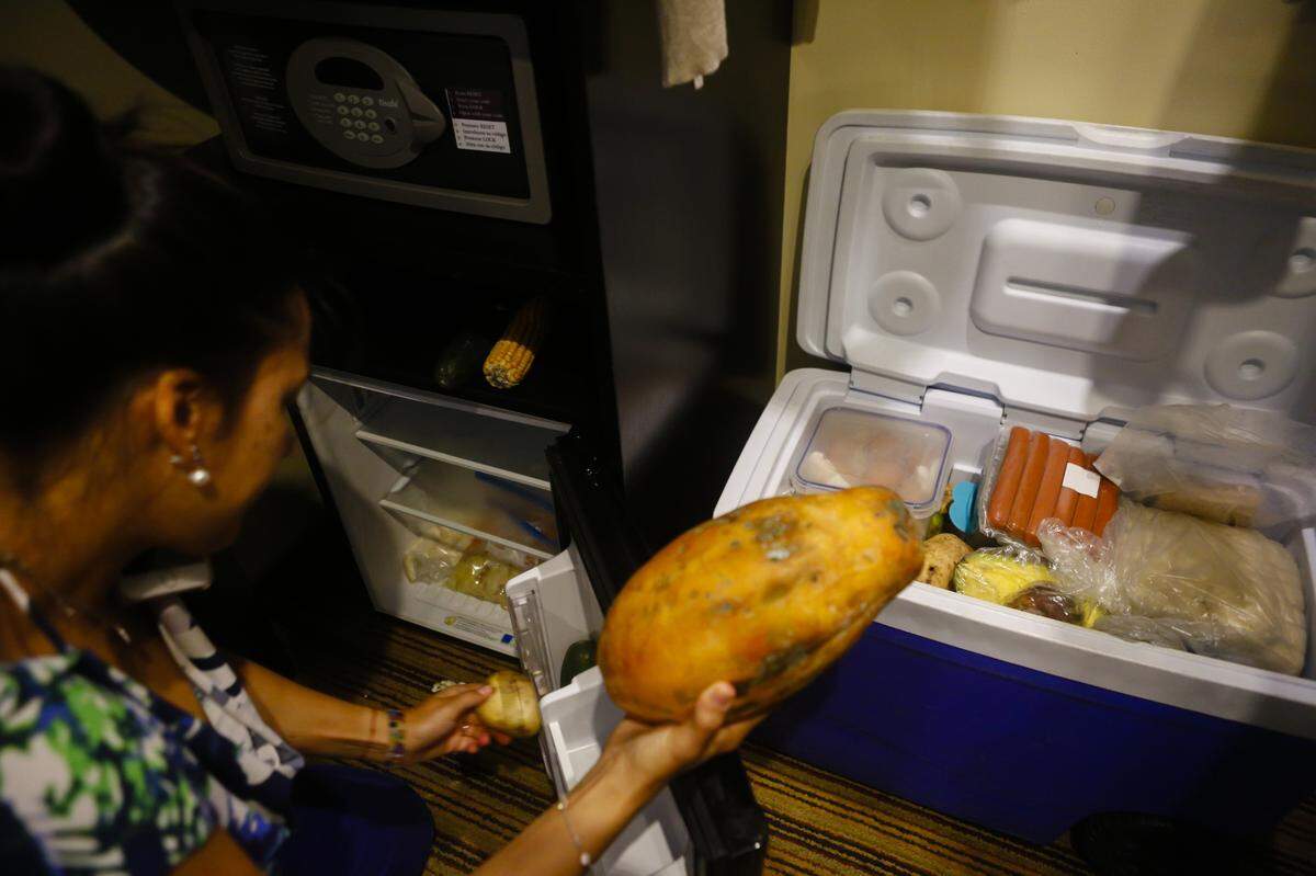 Una mujer saca comida del refrigerador de un hotel y la pone en una nevera con hielo el 13 de marzo del 2019 en Caracas.